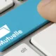 Touche de clavier bleue marquée « Mutuelle » sous un doigt