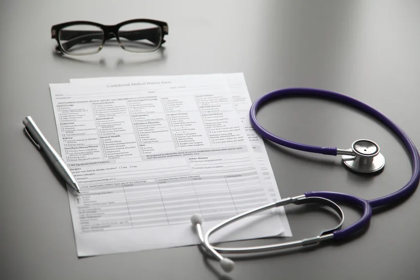 Stethoscope on the grey desk Questionnaire médical, lunettes, stylo et stéthoscope posés sur une table, pour l'assurance de prêt
