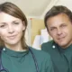 Un vétérinaire et sa conjointe en blouse verte, stéthoscope autour du cou, dans la clinique