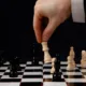 Main déplaçant un pion sur un échiquier, image de la stratégie de transmission de la clinique