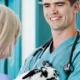 Vétérinaire souriant en tenue verte tenant un chiot dalmatien devant une collaboratrice