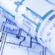 Plans d'architecte roulés posés sur une table, pour l'achat des murs de la clinique